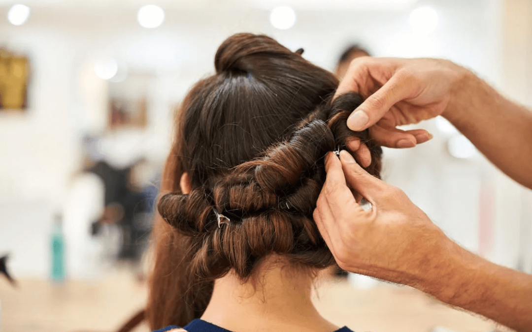 Friseur bearbeitet Haare von Kundin